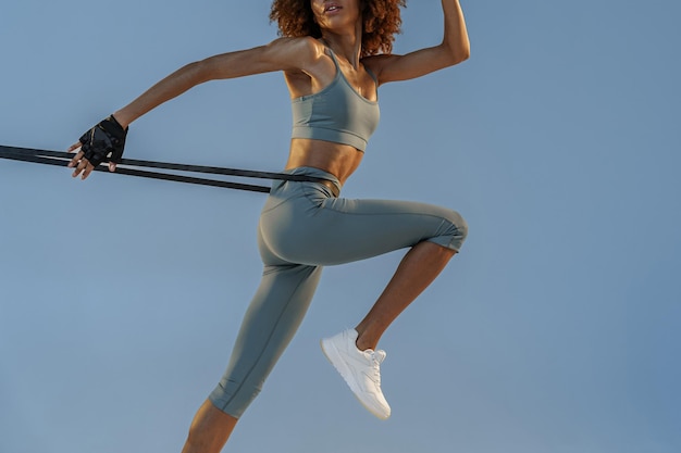 Sportieve vrouw die springende oefening met weerstandsband op studioachtergrond doet
