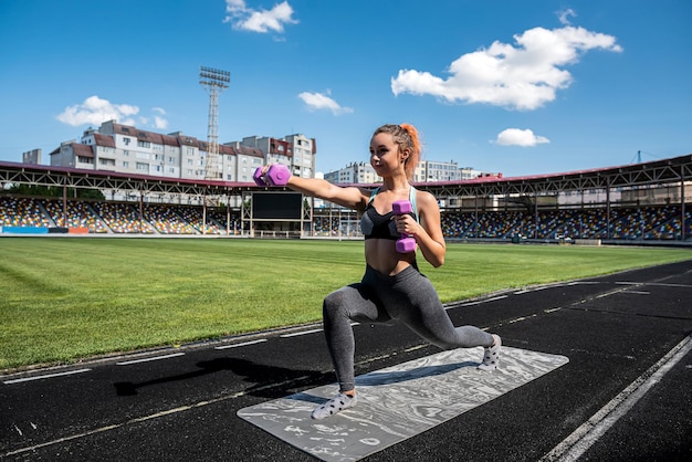 Sportieve vrouw die zich uitstrekt of yoga doet op het circuit van het stadion. concept van flexibiliteit