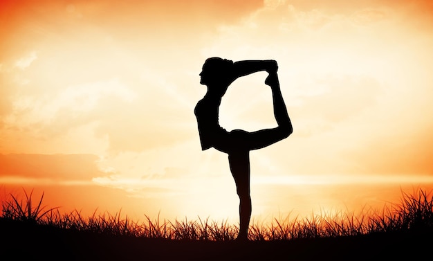 Sportieve vrouw die zich uitstrekt terwijl ze op één been balanceert tegen de oranje zonsopgang