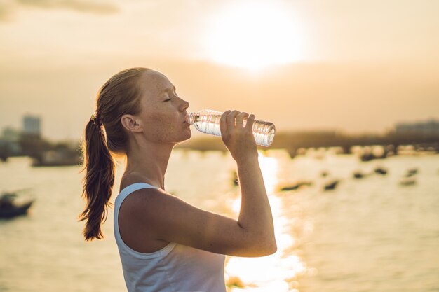 Sportieve vrouw drinkwater buiten op zonnige dag