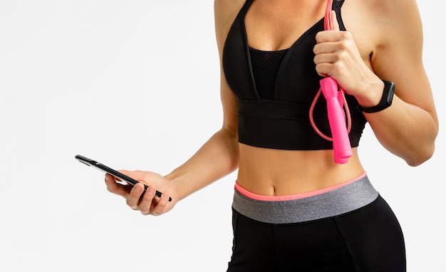 Sportieve vrouw fitness tracker met smartphone op witte ruimte controleren. Cardio training concept.