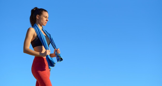 Foto sportieve vrouw met handdoek buitenshuis blauwe hemel achtergrond kopie ruimte