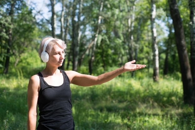 Sportieve vrouw met koptelefoon toont door haar hand Sportief lifestyle concept