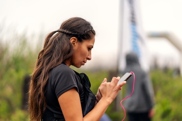 Sportieve vrouw met mobiele telefoon en koptelefoon voor het runnen van competitie