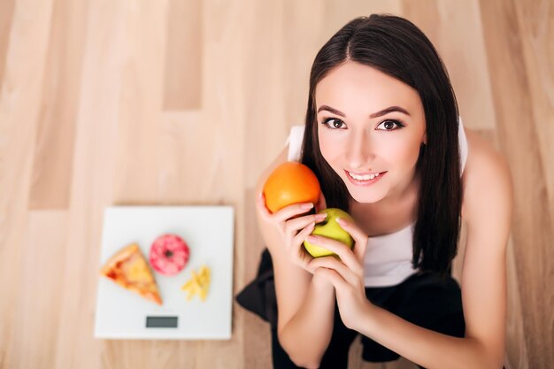 Sportieve vrouw met schaal en groene appel en sinaasappel