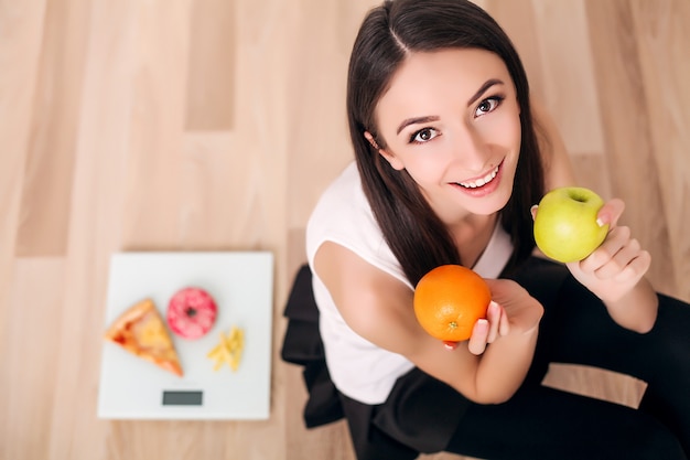 Sportieve vrouw met schaal en groene appel en sinaasappel