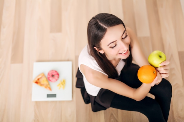 Sportieve vrouw met schaal en groene appel en sinaasappel