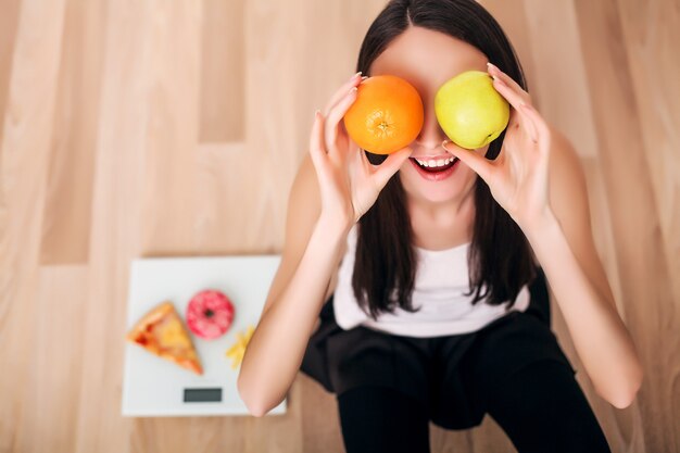 Sportieve vrouw met schaal en groene appel en sinaasappel