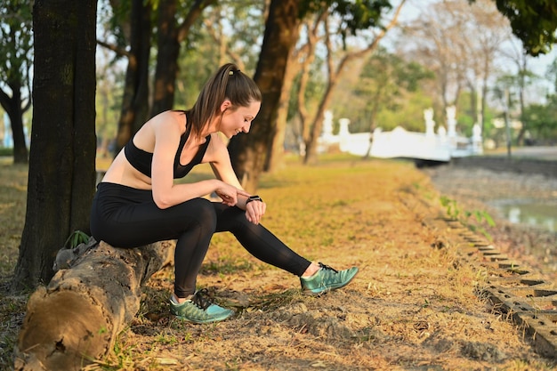 Foto sportieve vrouw ontspannen na ochtend en training hartslag controleren op smartwatch gezonde levensstijl sport en technologie concept