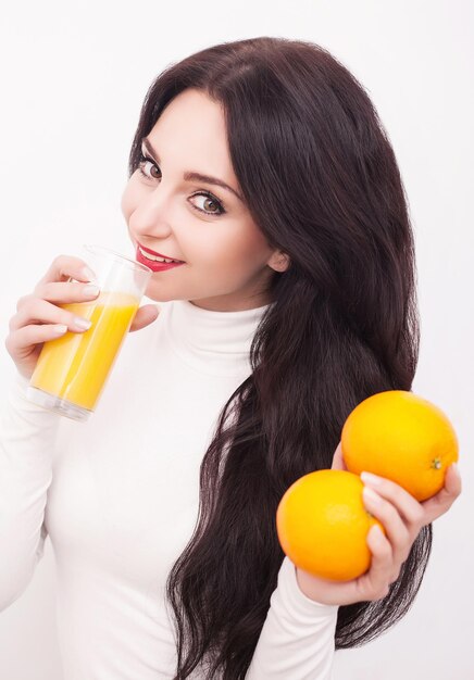 Sportieve vrouw op witte achtergrond met glas jus d'orange.