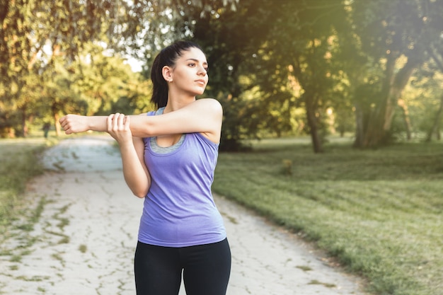 Sportieve vrouw opwarmen voor training, yoga of fitness buiten in zonsopgang of zonsondergang.