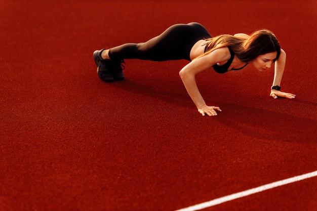 Sportieve vrouw poseren met spieren in het stadion doen stretching praktijk flexibiliteit