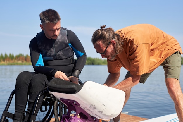 Sportinstructeur die een gehandicapte man helpt bij het monteren van adaptieve uitrusting