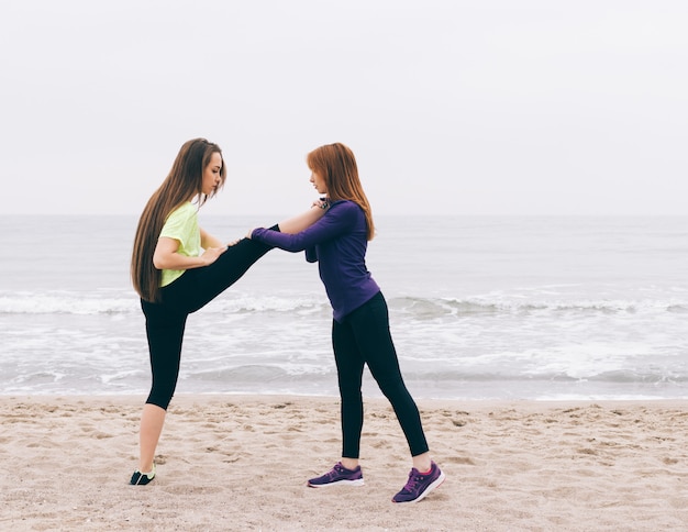 Sportinstructeur helpt het meisje om zich uit te strekken op het strand