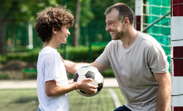 Sportive adult dad playing soccer with his son