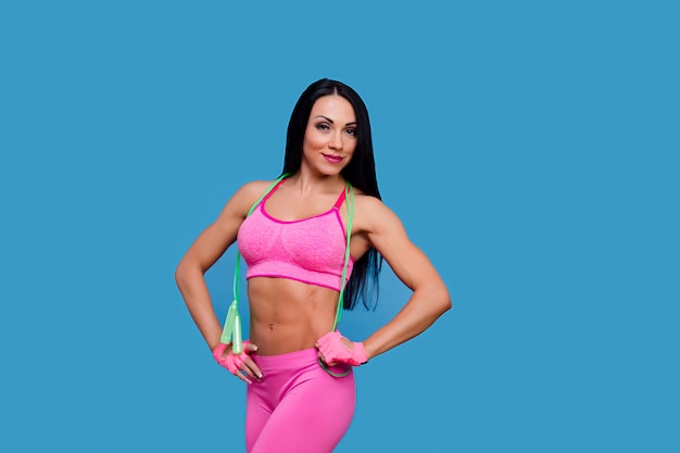Sportive brunette woman in the pink sportswear with skipping rope