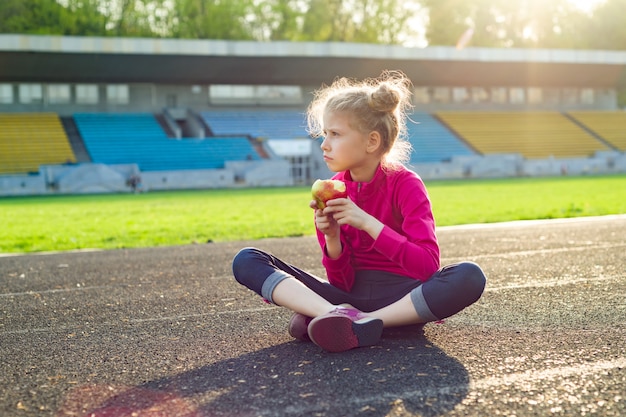 陽気な子供の女の子がリンゴを食べる