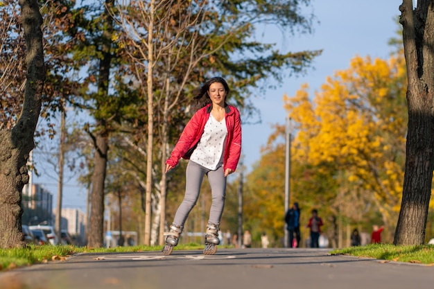 A sportive girl is rollerblading in an autumn park