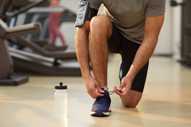 Sportive Man Tying Shoes в помещении