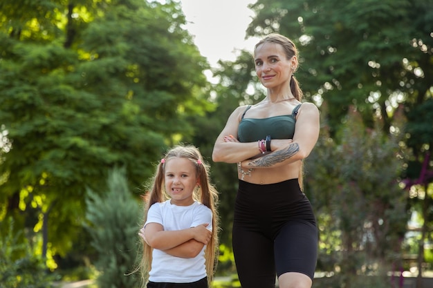 Sportive mom and little daughter posing in the park