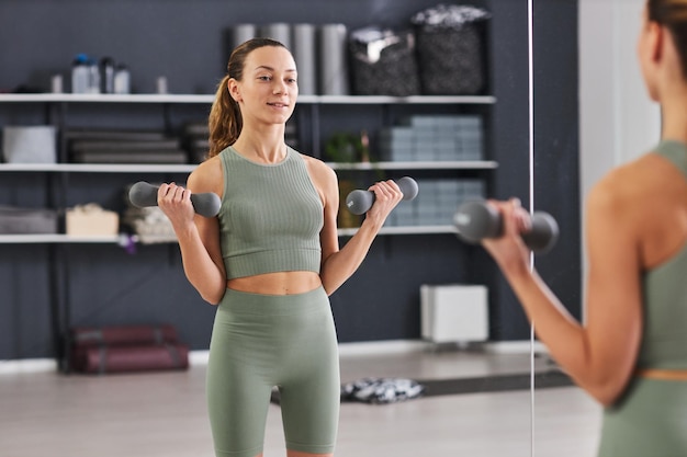 Sportive woman exercising with dumbbells in gym