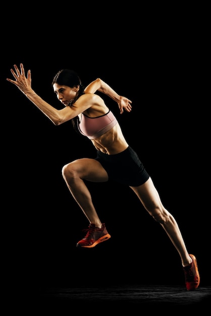 Sportive woman professional running athlete in uniform posing\
isolated over white studio background