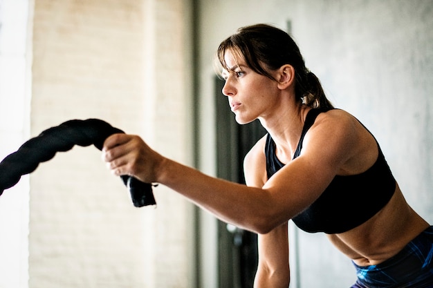 Sportive woman working out on the battle ropes