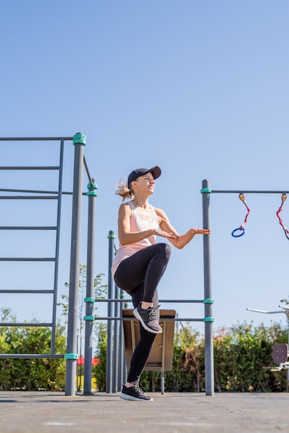 Sportive woman working out on the sports ground in sunny summer day