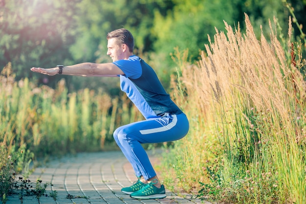 Спортивный молодой человек делает спортивные упражнения на открытом воздухе в парке