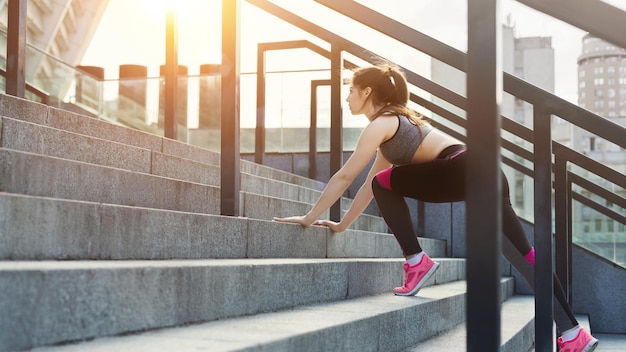 Sportive young woman exercising on stadium stairs