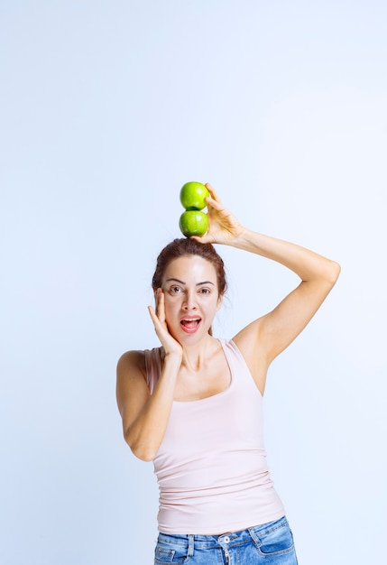 Sportive Young woman holding green apples over her head