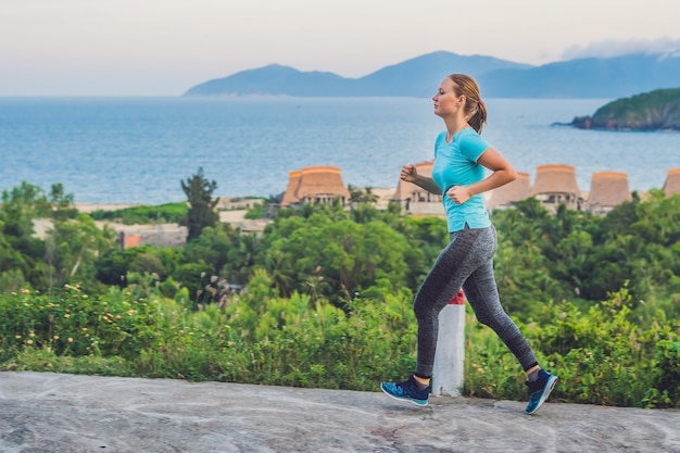 A sportive young woman is engaged in running against the sea