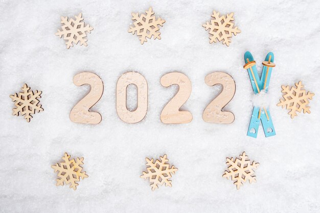 Sportjaar 2022. Helderblauw houten skispeelgoed, sneeuwvlokvorm en datum 2022 op witte sneeuw, plat gelegd, kopieerruimte. Liefde voor skiën. Favoriete wintersportconcept.