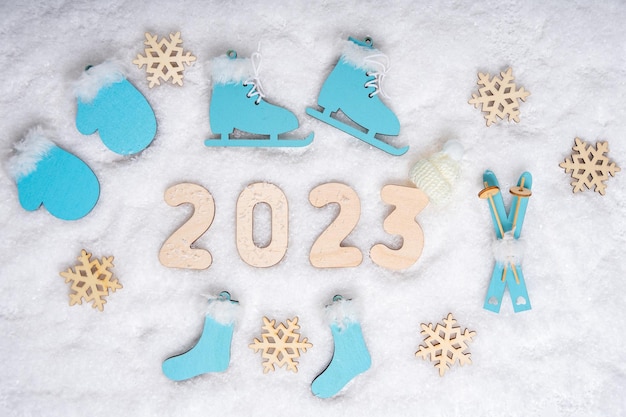 Sportjaar 2023 Sportset met felblauwe houten schaatsen ski's sleeën sneeuwvlokken en datum 2023 op witte sneeuw