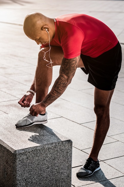 Sportkleding. aardige knappe man die naar zijn schoenen kijkt terwijl hij ze rijgt