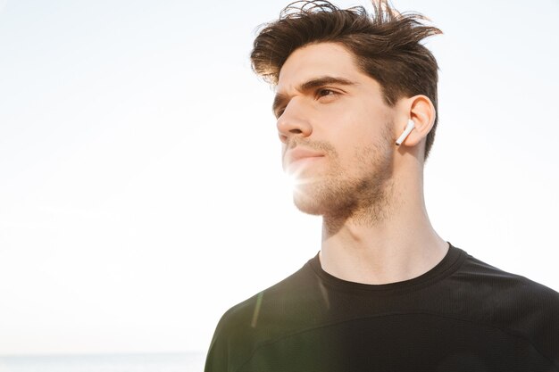 Sportman buiten op het strand luisteren muziek