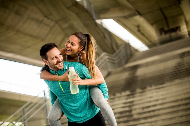 Sportman die een sportvrouw op zijn rug houdt