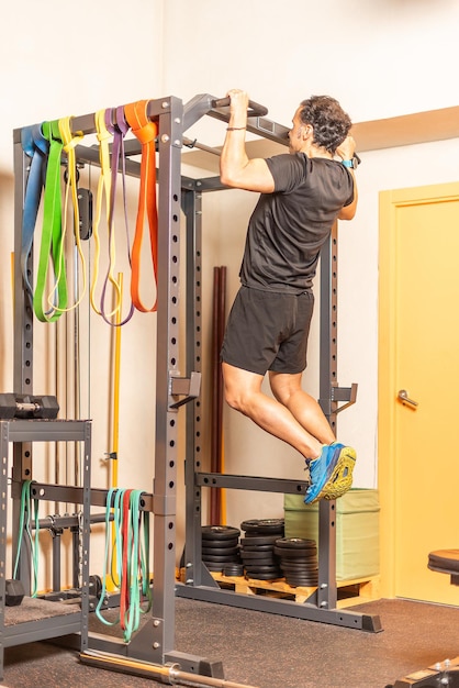 Sportman doet pull-ups met bar in de sportschool. Concept van oefeningen met apparatuur in de sportschool.