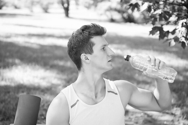 Sportman drinkwater op zonnige dag op natuurlijk zomerlandschap