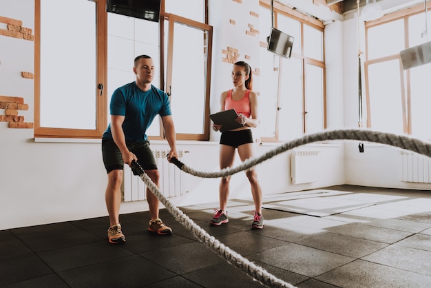 Sportman is aan het trainen in de sportschool met trainer