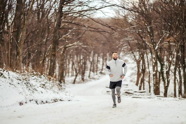 Sportman joggen in de natuur op sneeuw in de winter. Gezonde levensstijl, winterfitness, koud weer