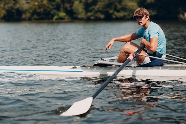 Sportman skiff man roeier roeien op boot