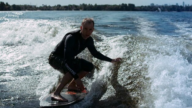 Sportman wakesurfen op golven in slow motion Ruiter die wakesurfstunt maakt