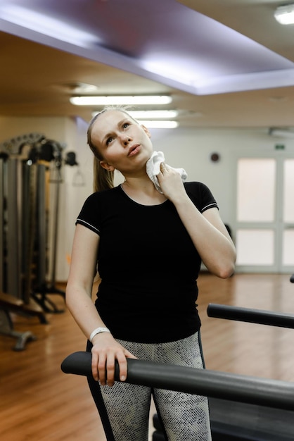 Sportmeisje in de thuisgymnastiek veegt zweet af met een witte, vermoeide vrouw van training die zweet afveegt met een handdoek in sportgymnastiek