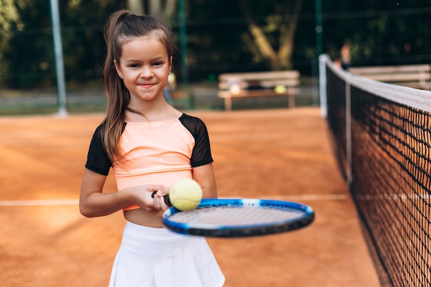 Sportmeisje met een racket en een tennisbal in haar handen op de tennisbaan