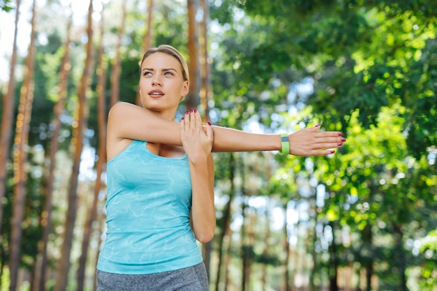 Sportoefening. Ernstige sportieve vrouw die haar hand beweegt tijdens het doen van een oefening