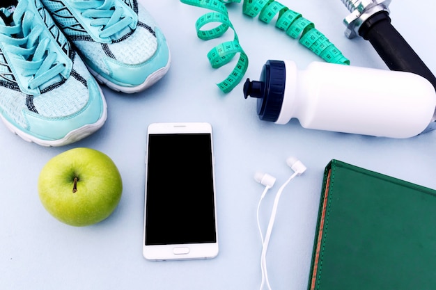 Sports background, sneakers, dumbbell, water, smartphone. 