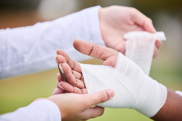 写真 スポーツ包帯と手に怪我をした人が応急処置をサポートし、試合やトレーニング後の応急処置や緊張をサポートします。クローズアップ事故と医師がガーゼ傷や解剖学的外傷を持つアスリートを支援します。