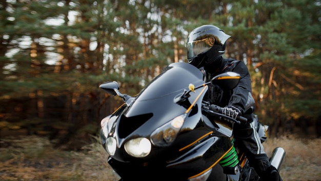 Motociclista sportivo che indossa un casco e indumenti protettivi in pelle su una bici sportiva veloce