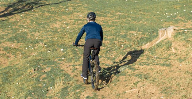 Sports brutal bearded guy on a modern mountain bike cyclist on\
the green hills in the spring